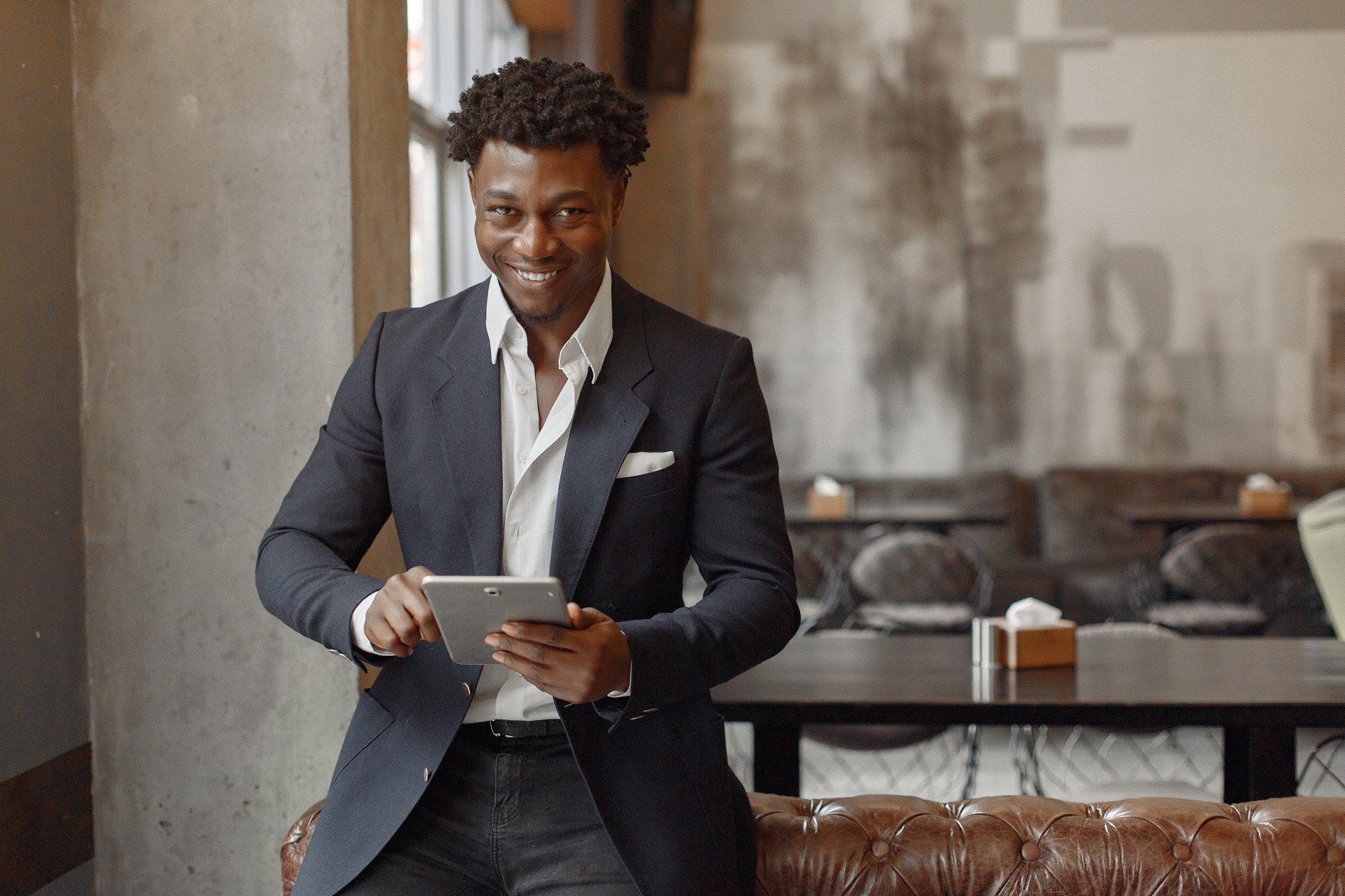 African in a suit on a tablet smiling at the camera