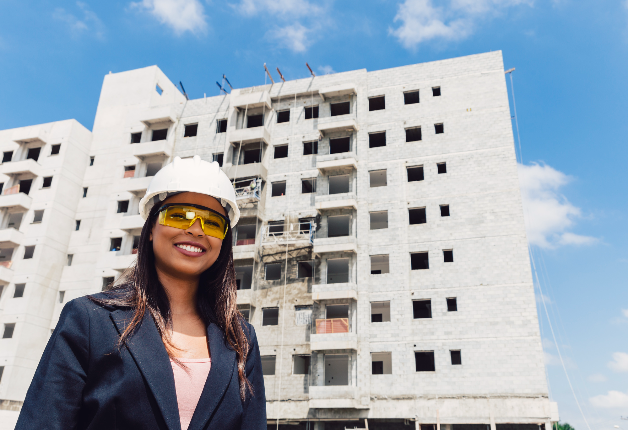 African lady wearing a construction helmet infront of a construction building