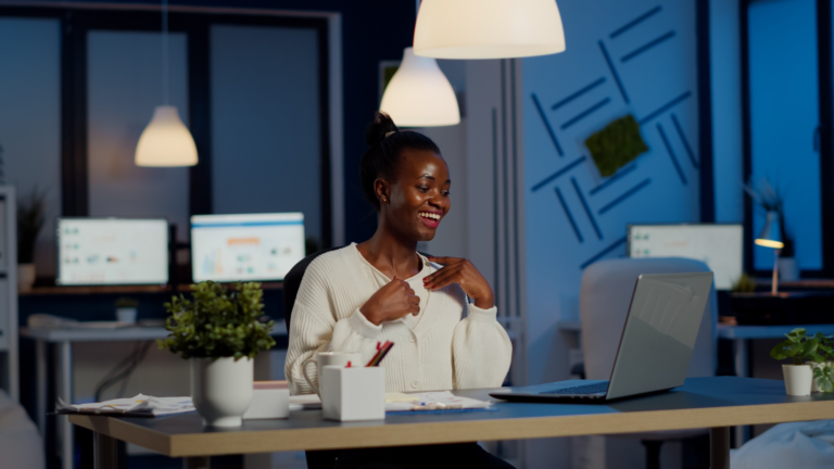 Young lady in an office smiling at her latop