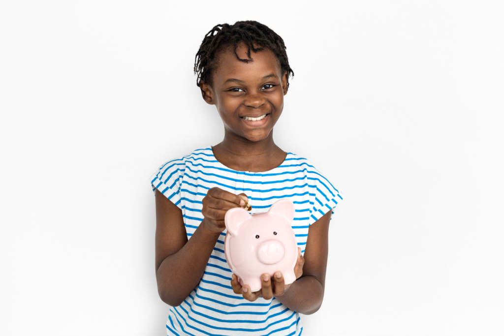 Image of a young happy child holding a piggy bank.